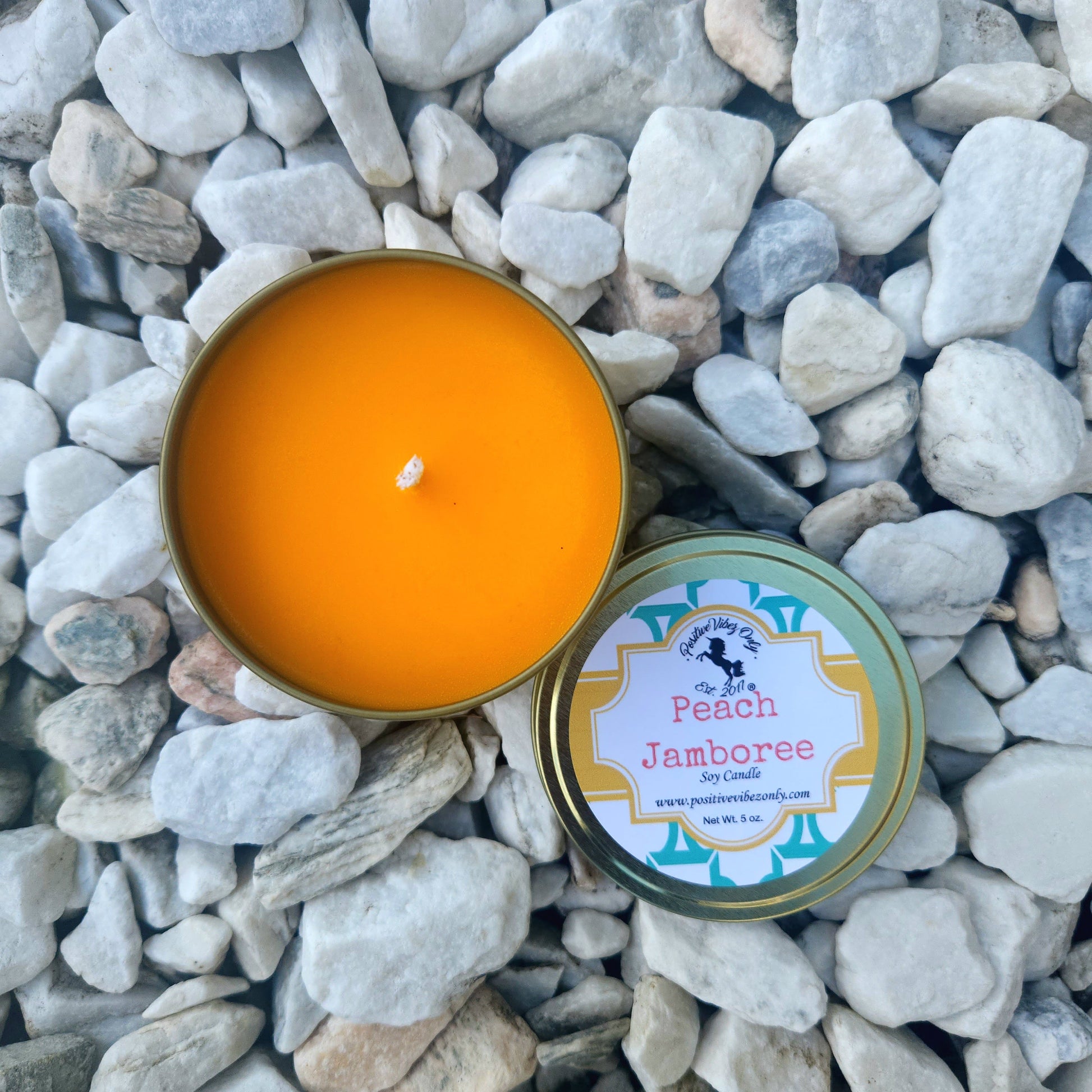 Peach Jamboree candle in a tin on pebbles